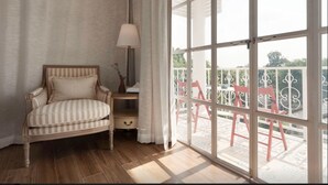 A room with a striped sofa, a lamp, and a view of a balcony with red chairs. - Meesuk Boutique House (Chiang Mai)