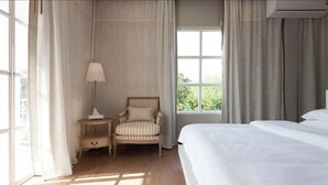 A hotel room with a large bed, a chair, a nightstand, and a window with curtains. - Meesuk Boutique House (Chiang Mai)