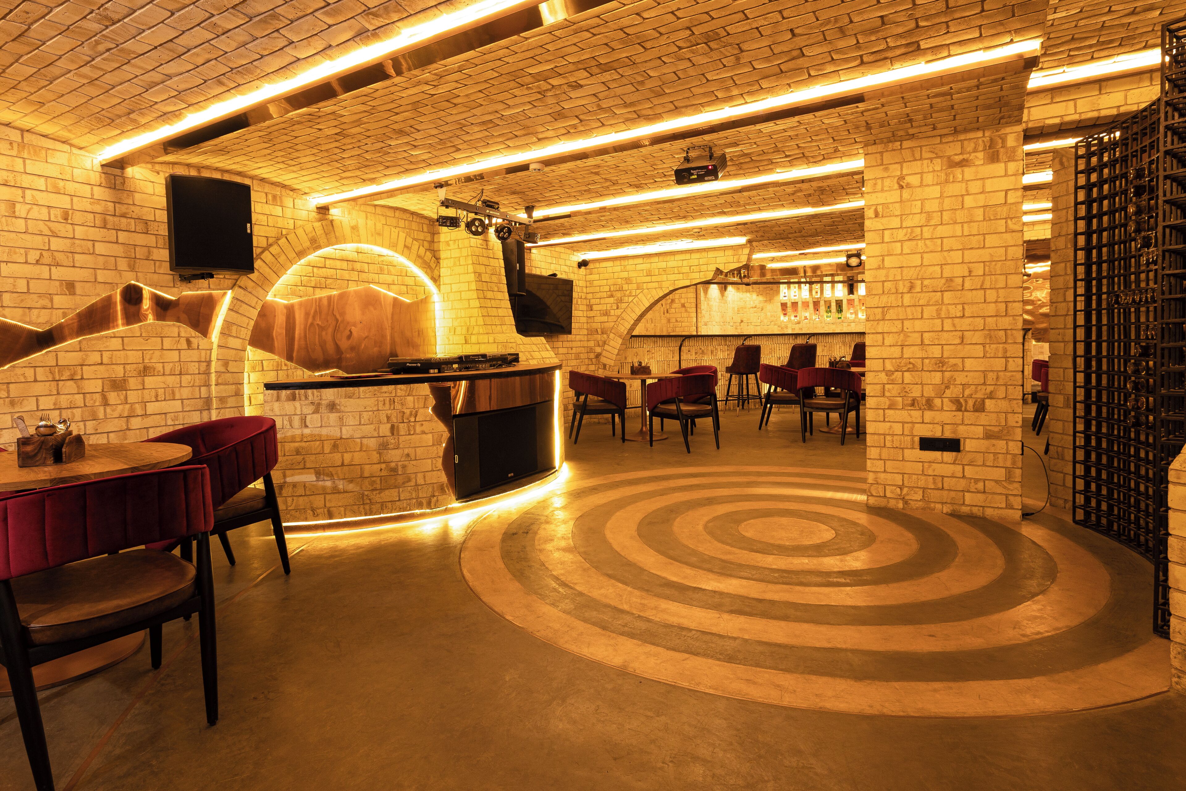 A restaurant with brick walls, a circular floor design, and a bar area.