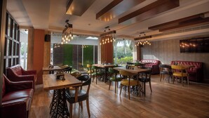 Ein Restaurant mit Holztischen und -stühlen, einer roten Lederauslage und hängenden Lampen.