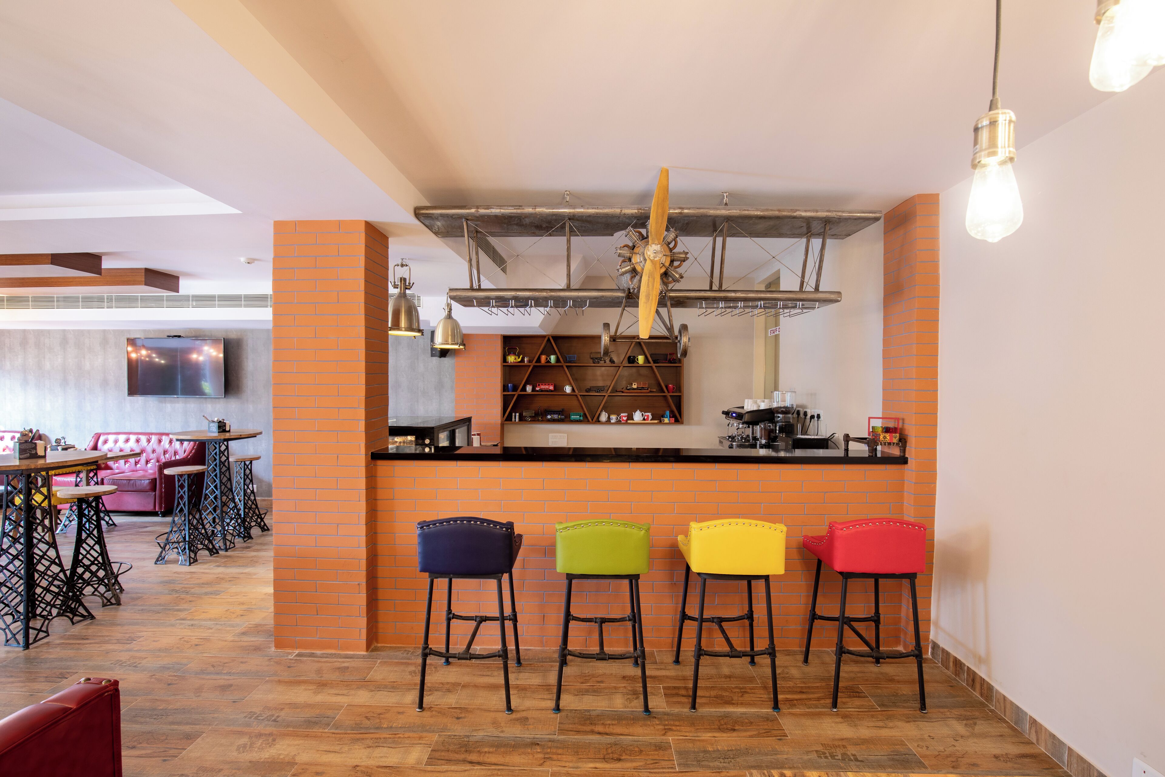 Un restaurant avec un mur d’accent en briques, un coin bar avec des tabourets et une cuisine moderne en arrière-plan.