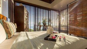 A modern room with a large bed, a tray with flowers, and a view of the ocean through large windows. - L2 Residence (Koh Samui)