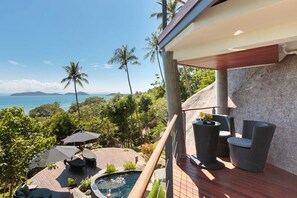 A deck with outdoor seating, a hot tub, and a view of the ocean.