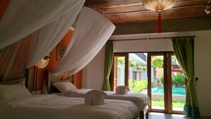 A room with two beds, a canopy, a hanging lantern, and a view of a pool. - Garden Yard Inn Chiangmai (Chiang Mai)