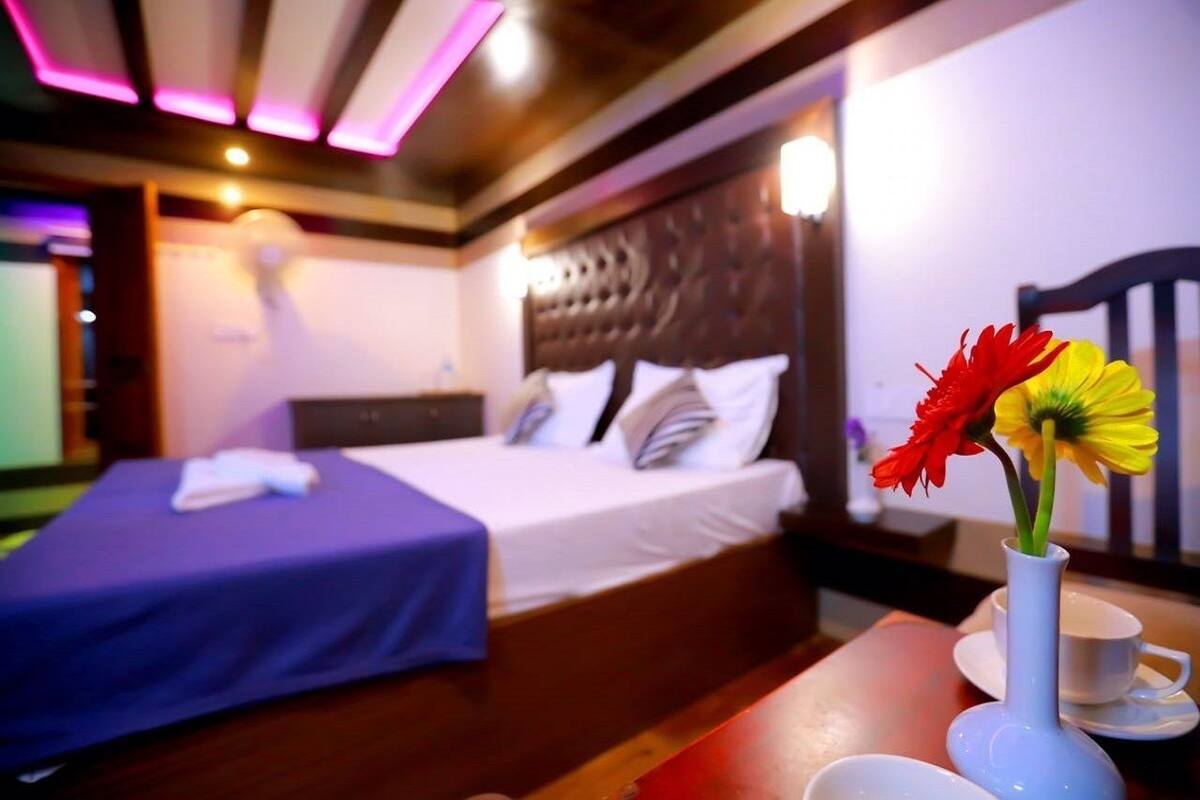 Une chambre d’hôtel avec un lit, une table de chevet ornée d’un vase de fleurs et une table avec une tasse et une soucoupe.