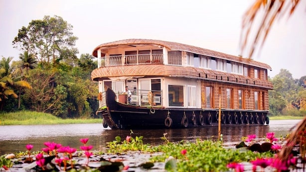 A houseboat with a thatched roof, windows, and a deck area.