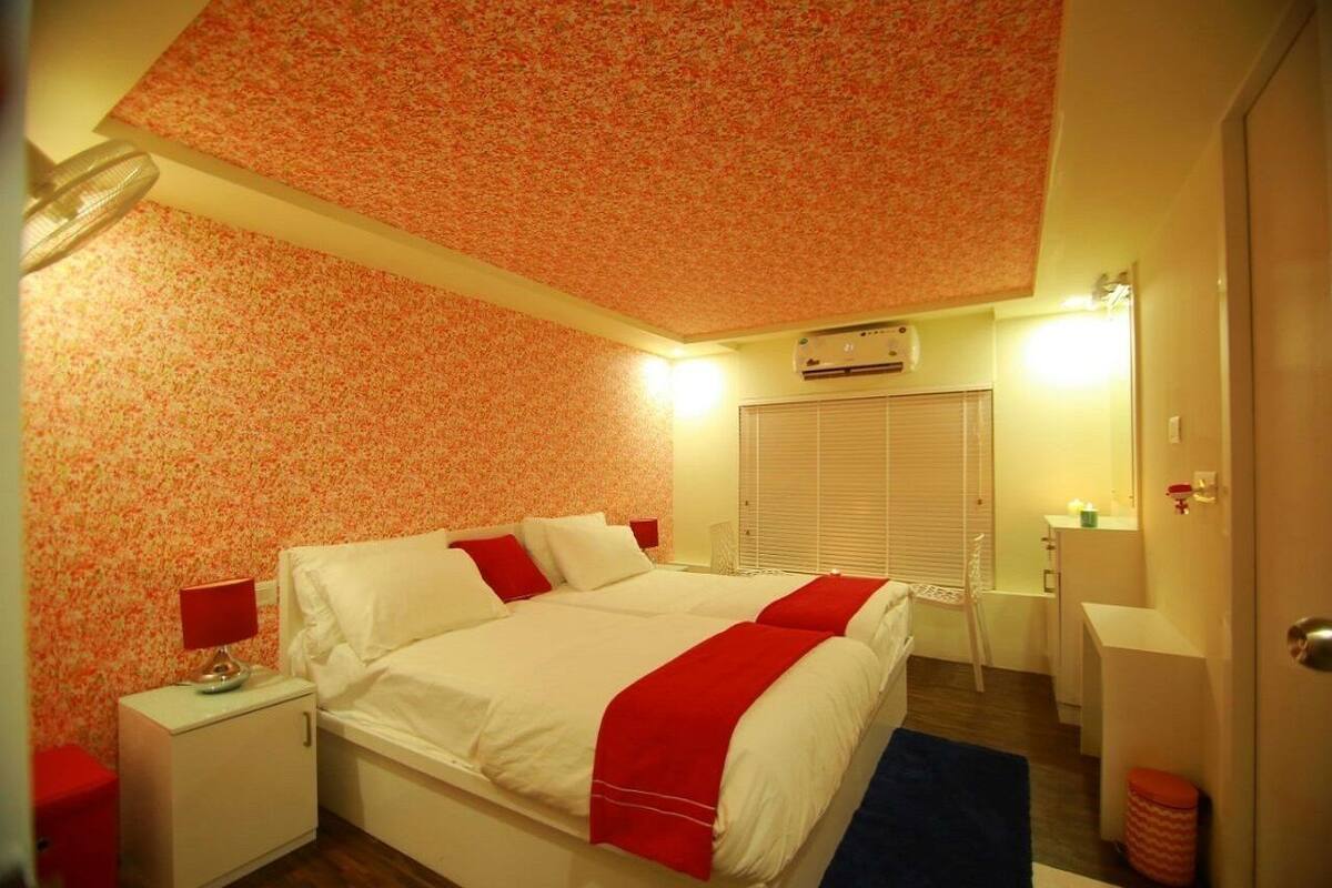 Une chambre à coucher avec un lit, une table de chevet, une lampe et une fenêtre avec des stores.