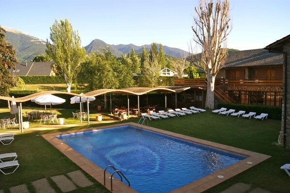 Una piscina al aire libre de temporada, sombrillas