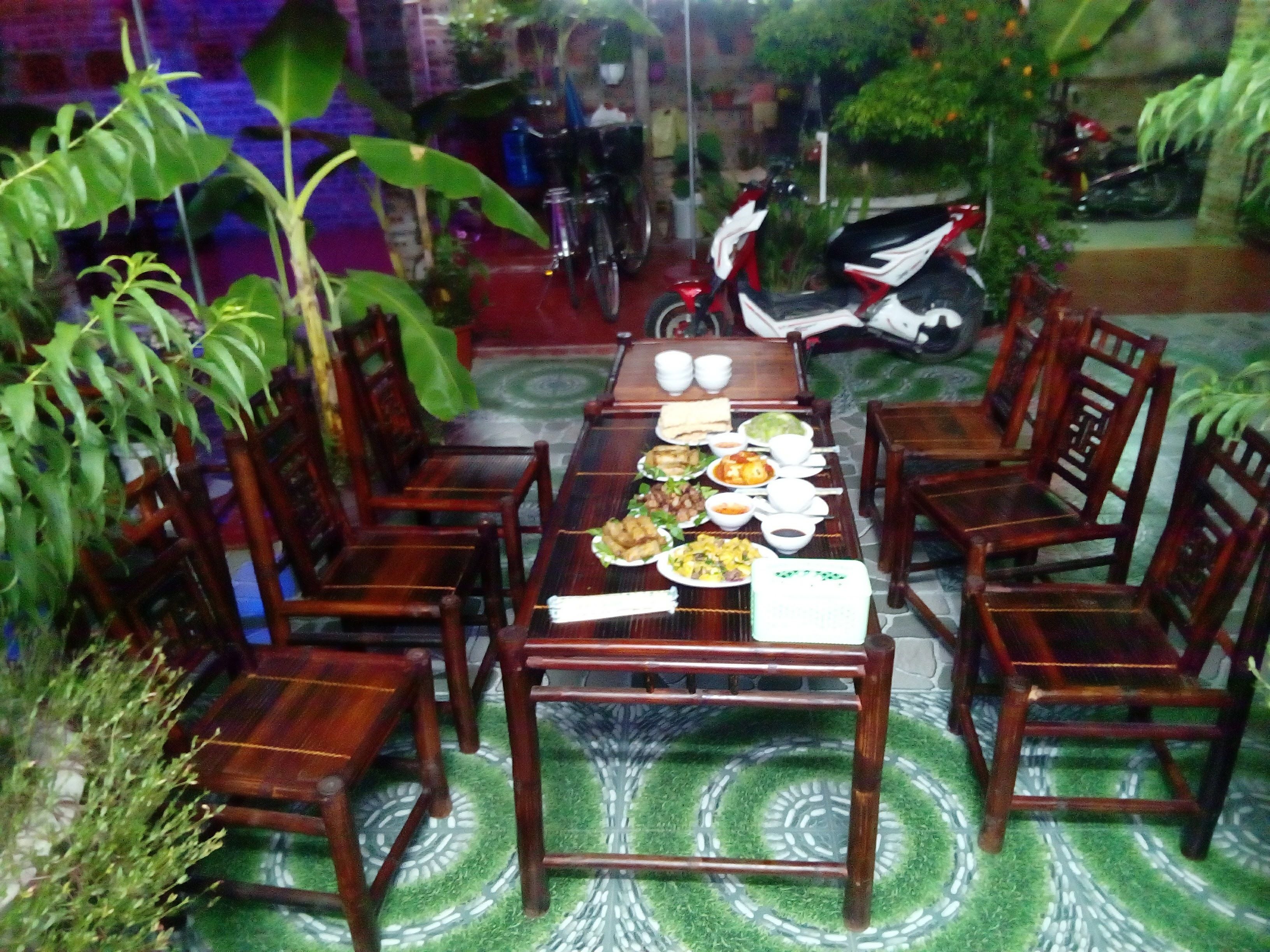 Uma sala de jantar com uma mesa de madeira comprida posta para refeição, rodeada por cadeiras de madeira.
