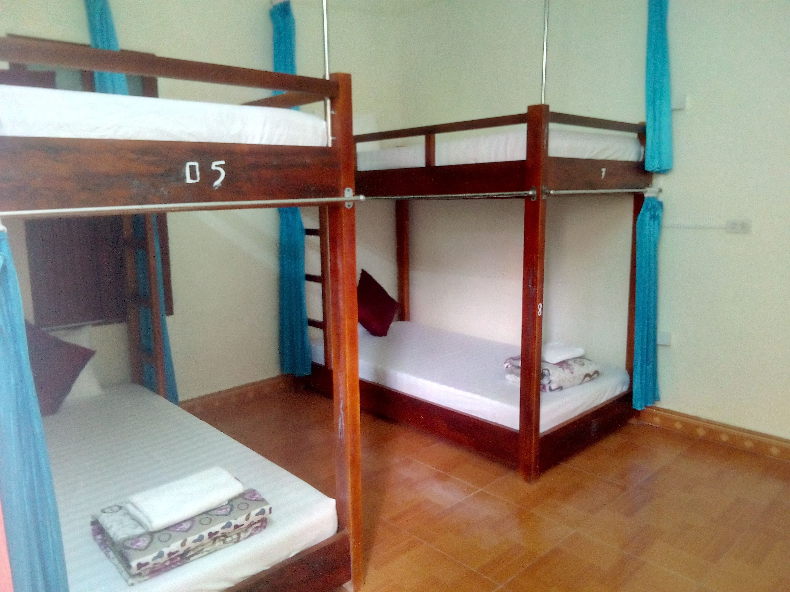 Une chambre avec un lit superposé, dont les montants sont en bois et les rideaux sont bleus.