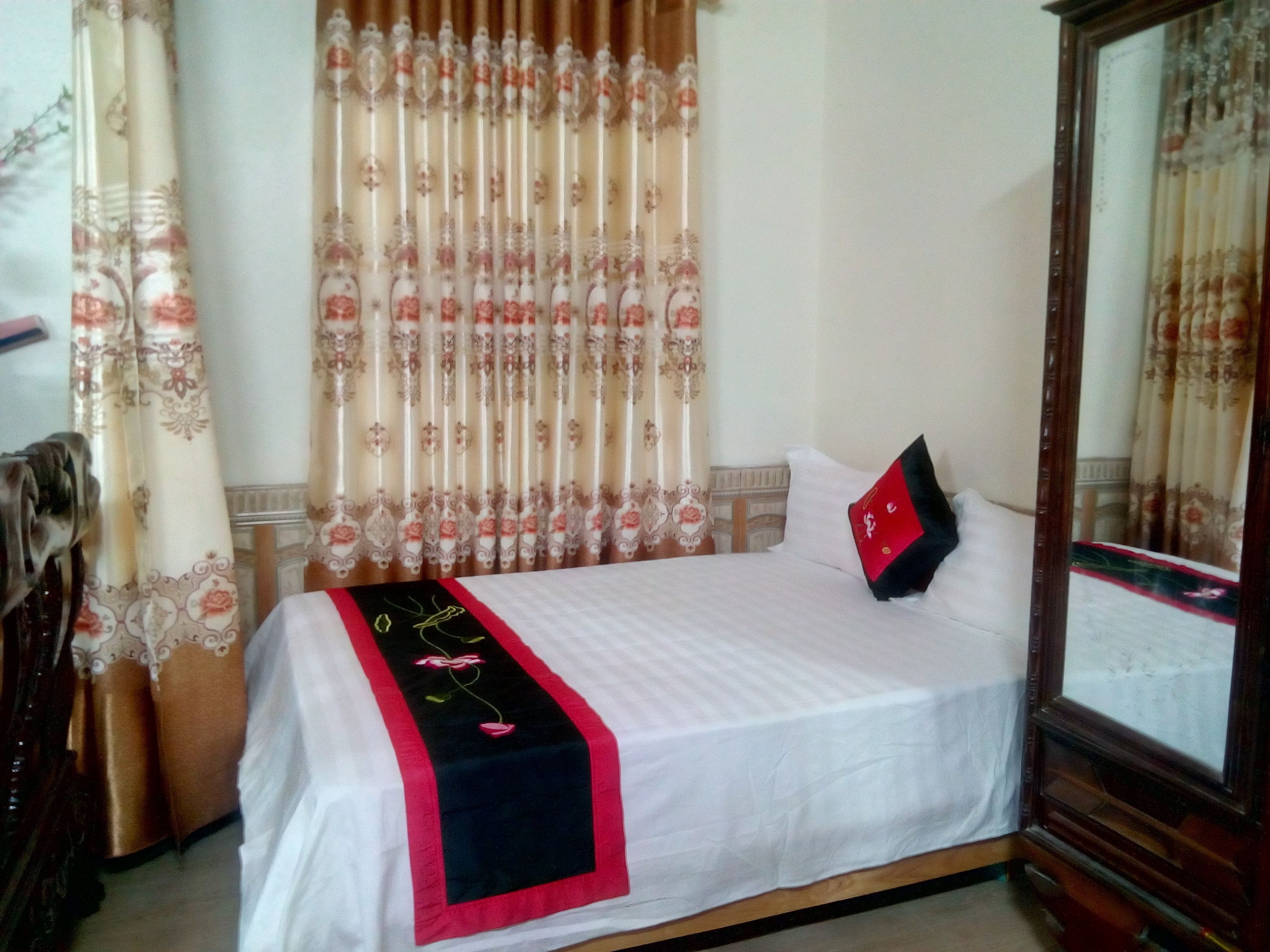 Un lit bien fait, recouvert d’une couverture blanche et agrémenté d’un coussin décoratif noir et rouge.