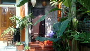 Una casa tradizionale con un muro in mattoni, una porta in legno e gradini che conducono a un portico.