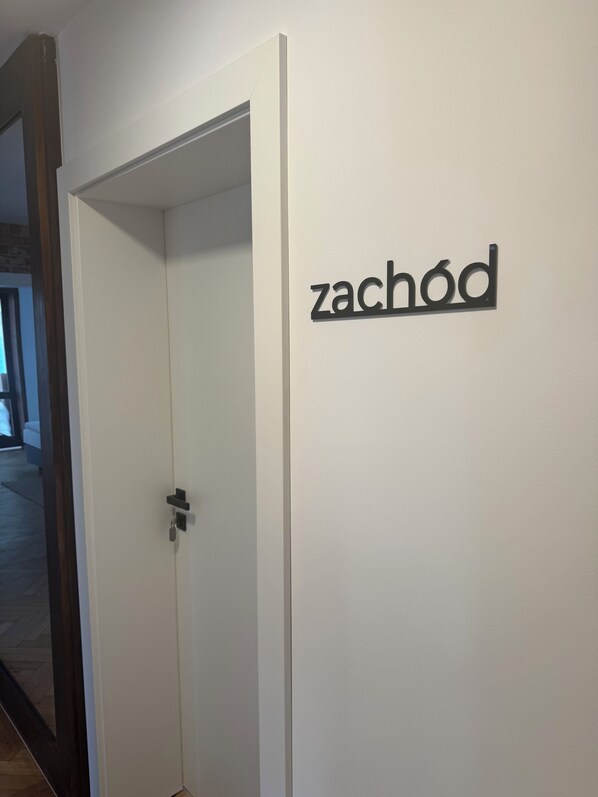 A white door with a metal handle and a sign above it that reads "zachód". - Pensjonat Barbara (Wladyslawowo)