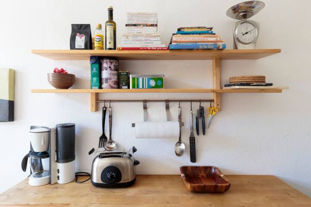 Een keuken met een koffiezetapparaat, een broodrooster en een houten kom op het aanrecht.