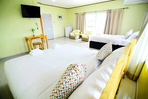 A hotel room with a large bed, a desk with a chair, a television, and a window with curtains. - Laksasuk House (Mae Sot)