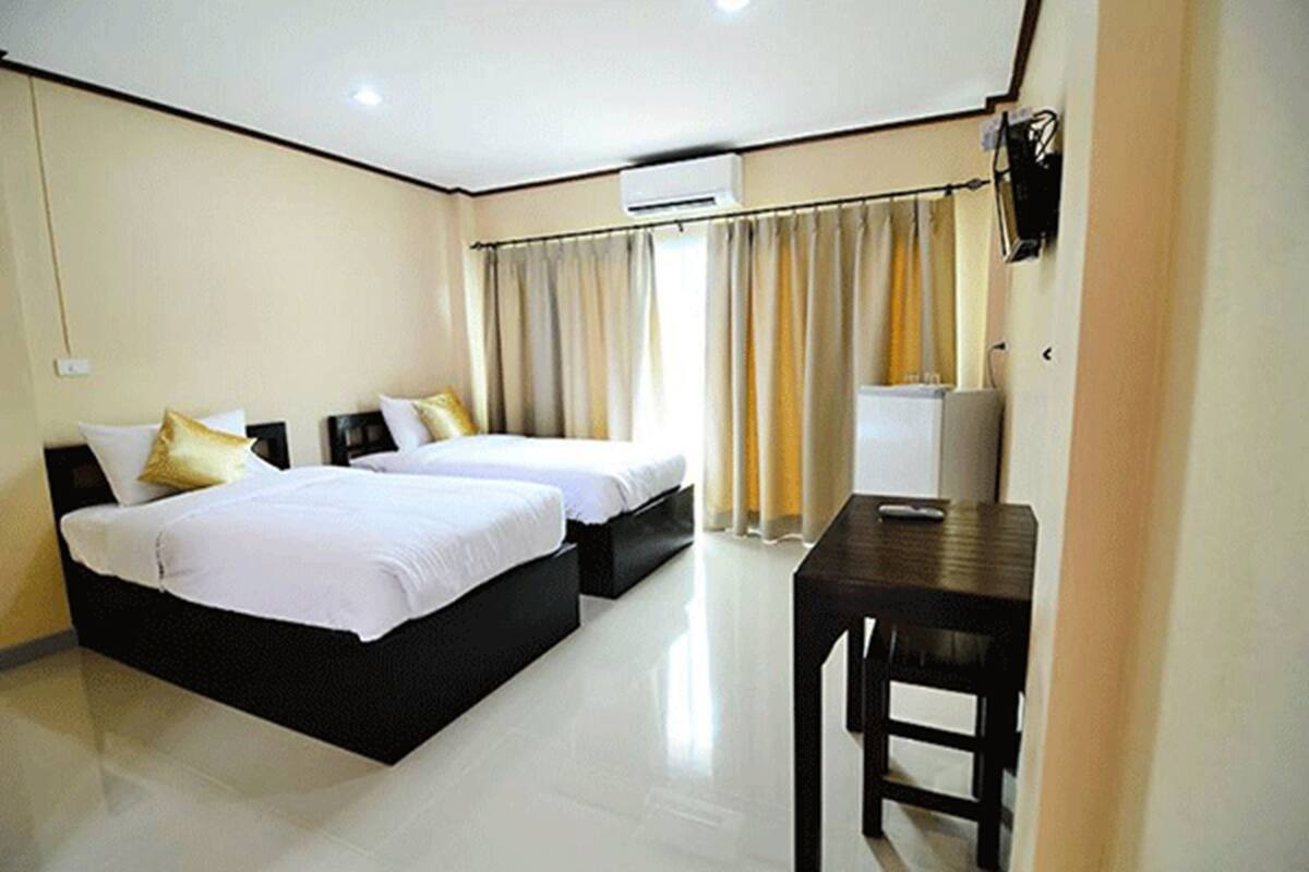 Quarto de hotel com duas camas, uma escrivaninha e um ar condicionado.