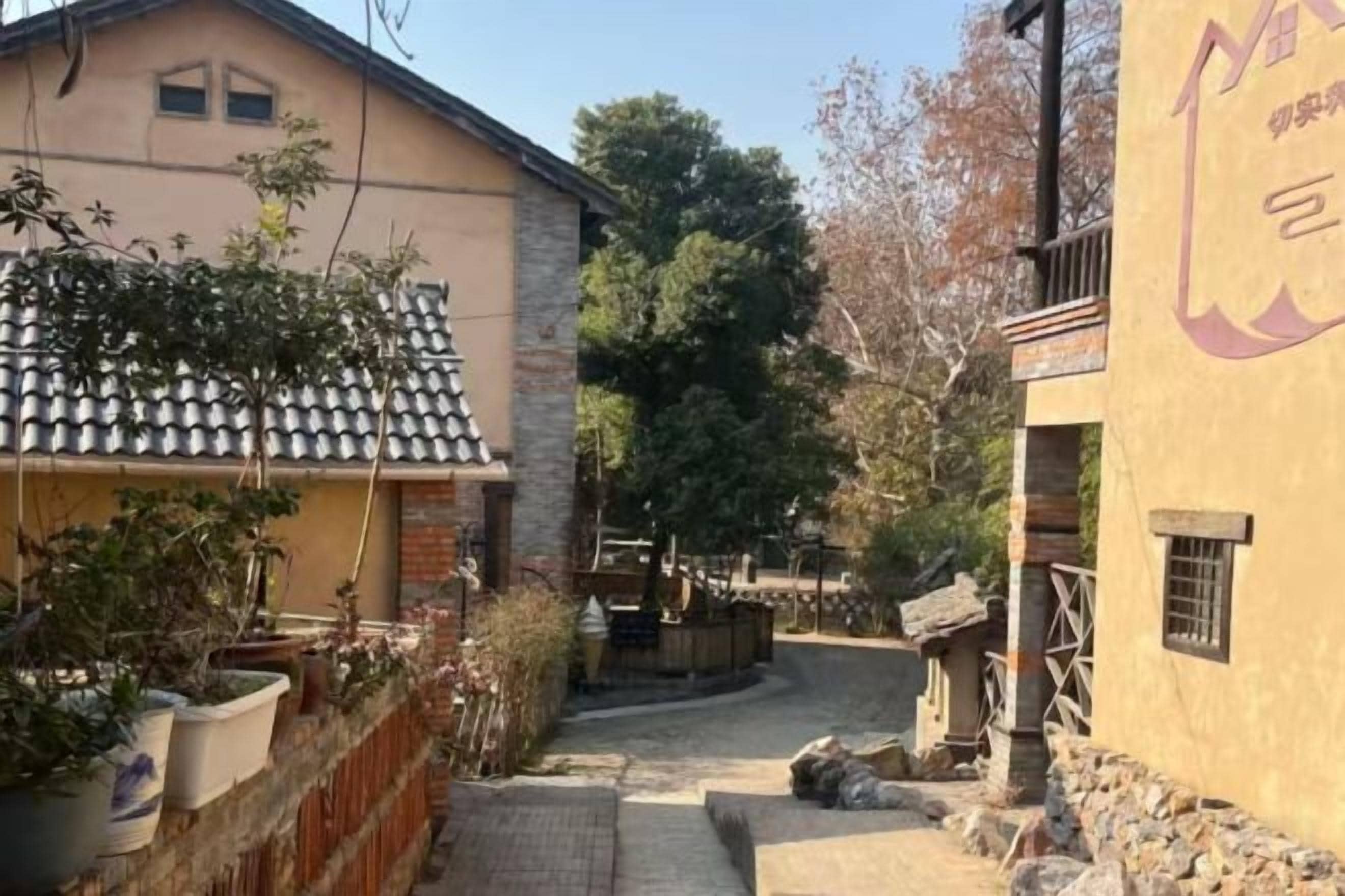 Un estrecho callejón con un edificio a la izquierda y un muro de piedra a la derecha.