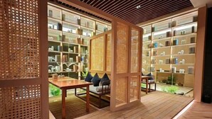 A modern interior with a wooden floor, a seating area with cushions, and shelves with various items.