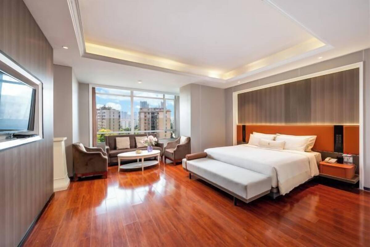 Une chambre d’hôtel moderne avec un grand lit, un canapé, une table basse et un téléviseur.