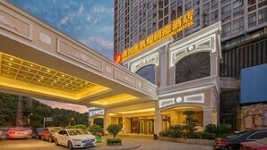 A hotel with a prominent entrance, a covered walkway, and a parking area.