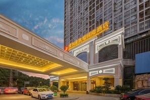 Un hotel con una entrada destacada, un corredor cubierto y un estacionamiento.