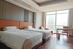 Een hotelkamer met twee bedden, een bureau en een groot raam.