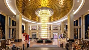 A grand lobby with a central column, a staircase, and a chandelier.