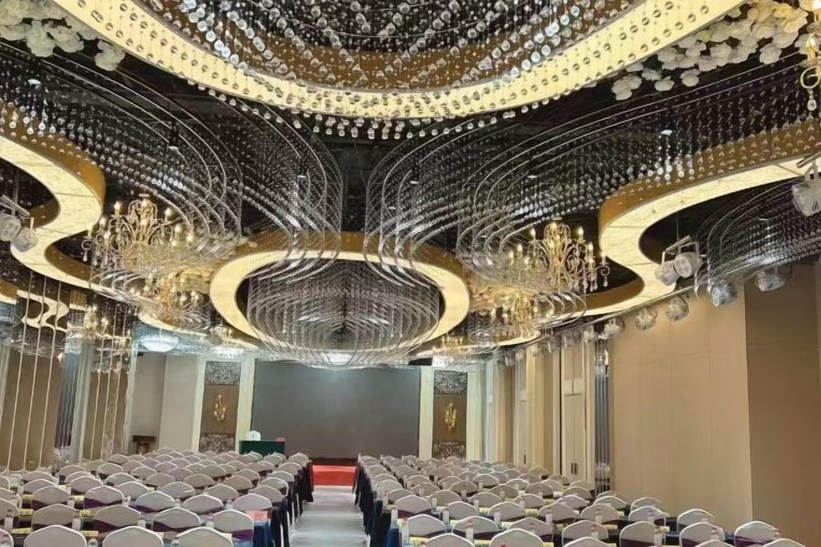Interior de un teatro con filas de asientos, un escenario central y candelabros ornamentales.