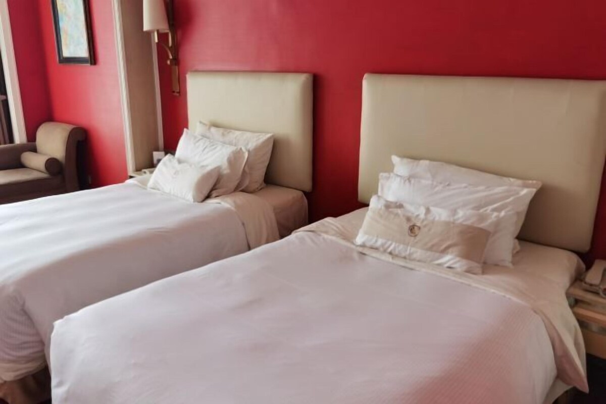 Een hotelkamer met twee bedden, elk voorzien van witte lakens en hoofdeinden.