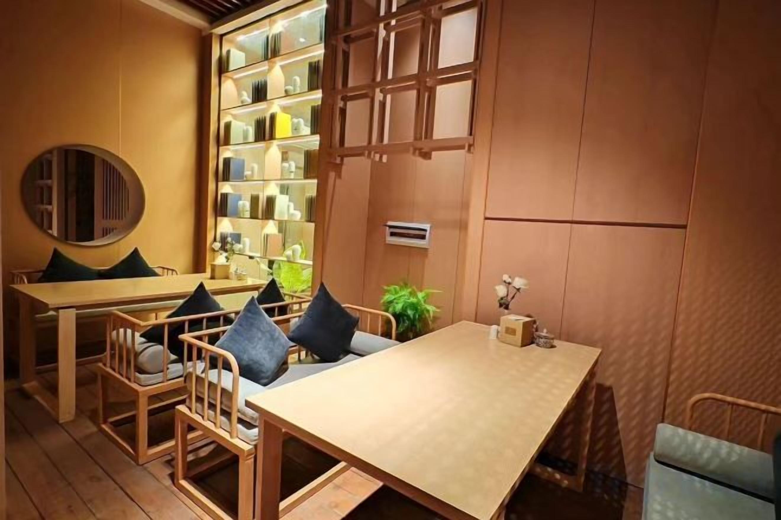 Un interior de madera con una mesa, sillas, una estantería y una planta.