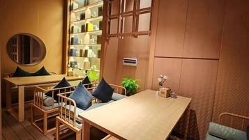 Un interior de madera con una mesa, sillas, una estantería y una planta.