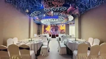 Un salón de banquetes con mesas redondas, sillas blancas y un techo decorativo.