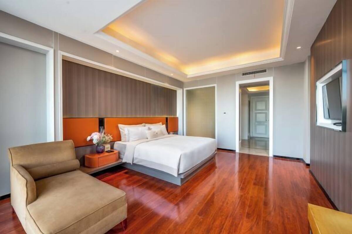 Une chambre d’hôtel avec un lit, un canapé, une table de chevet et un téléviseur.