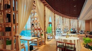 A library with wooden bookshelves, tables, and chairs.
