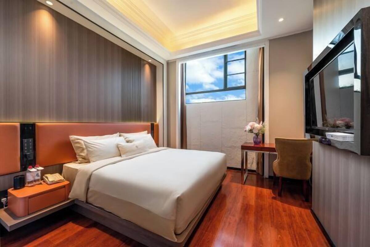 Une chambre d’hôtel avec un lit, une table de chevet, une télévision et une fenêtre donnant sur un beau paysage.