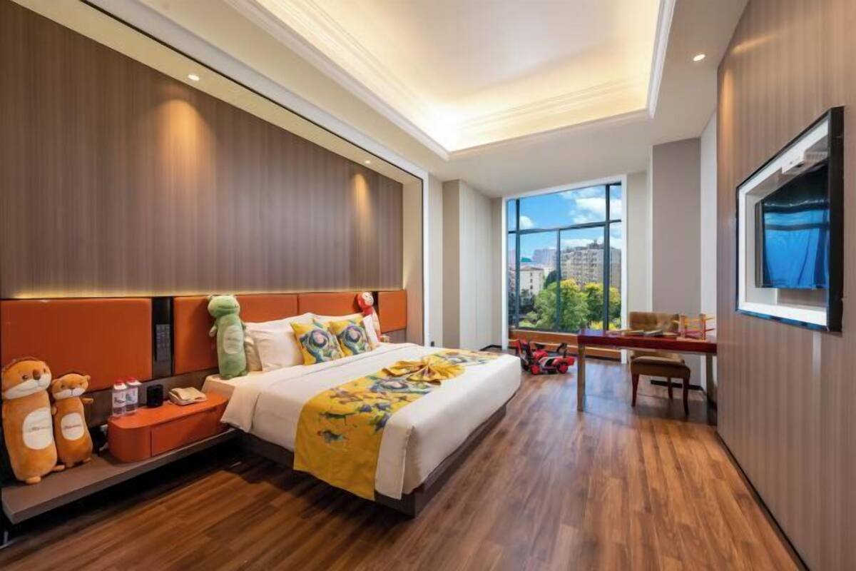 Une chambre d’hôtel avec un lit, un bureau, une télévision et une fenêtre donnant sur la ville.