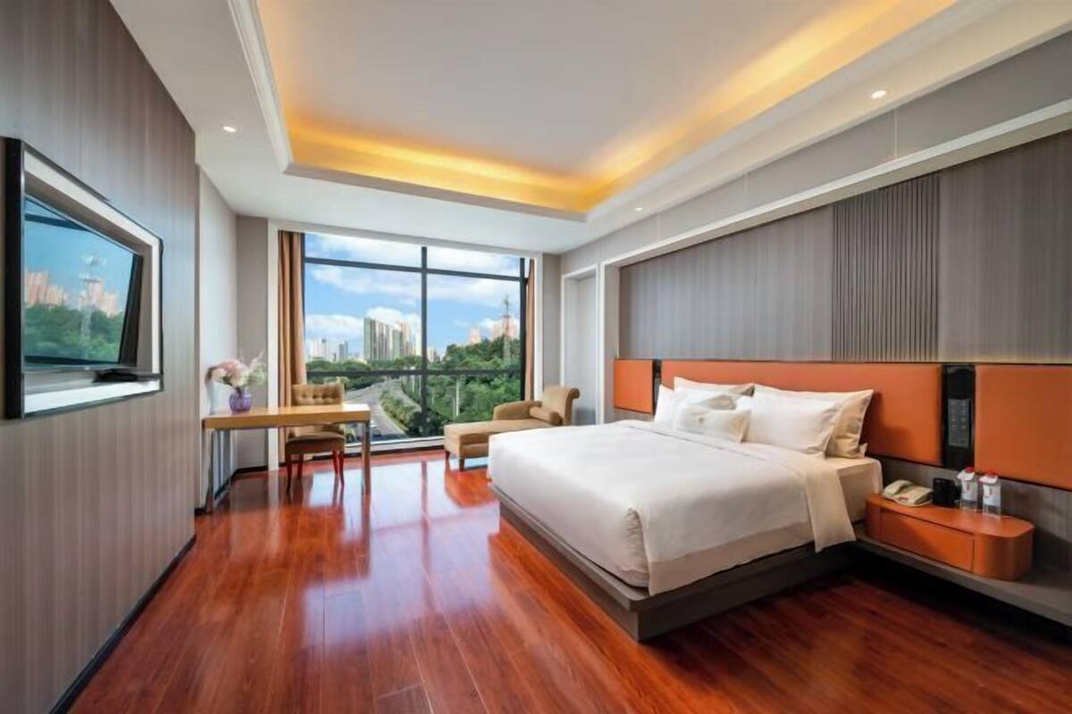 Une chambre d’hôtel moderne équipée d’un grand lit, d’un bureau, d’une chaise et d’un téléviseur.