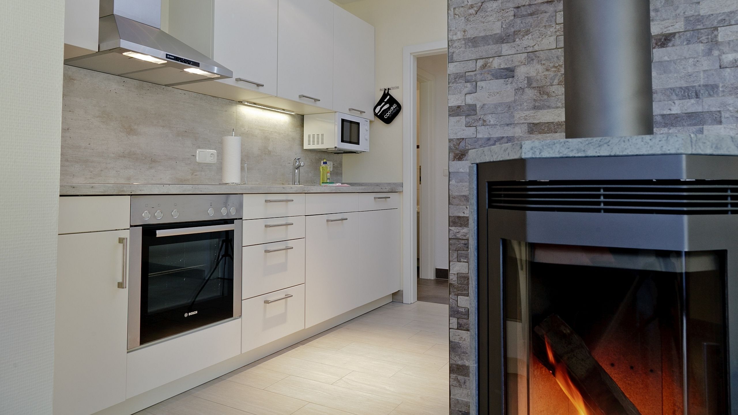 Uma cozinha moderna com eletrodomésticos de aço inoxidável, forno embutido e parede decorativa em pedra.