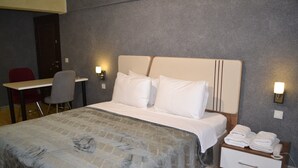 Una habitación de hotel con cama, mesita de noche, silla y escritorio.
