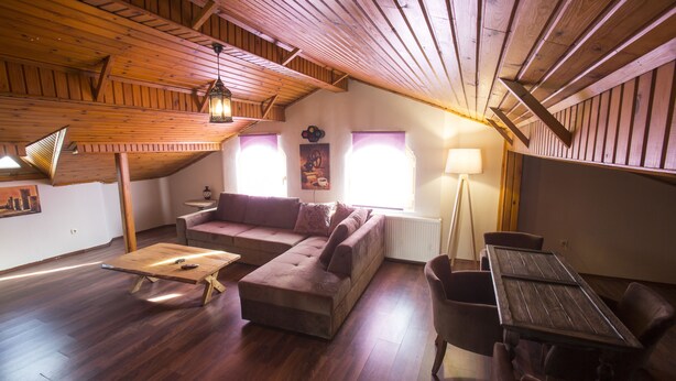 Un acogedor salón tipo loft con techo de madera, un sofá, una mesa de centro y una mesa de comedor con sillas.
