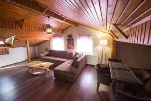 Ein gemütliches Loft mit offenem Holzboden, einer Couch, einem Couchtisch und einem Esstisch mit Stühlen.