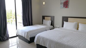 Ett hotellrum med två sängar, ett stort fönster med gardiner, en väggmonterad lampa och en tavla med röda telefonkiosker.