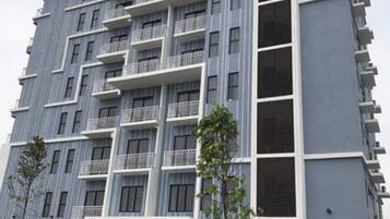A multi-story hotel with balconies, a sign for 'Boutique Hotel', and a parking area with a white car.