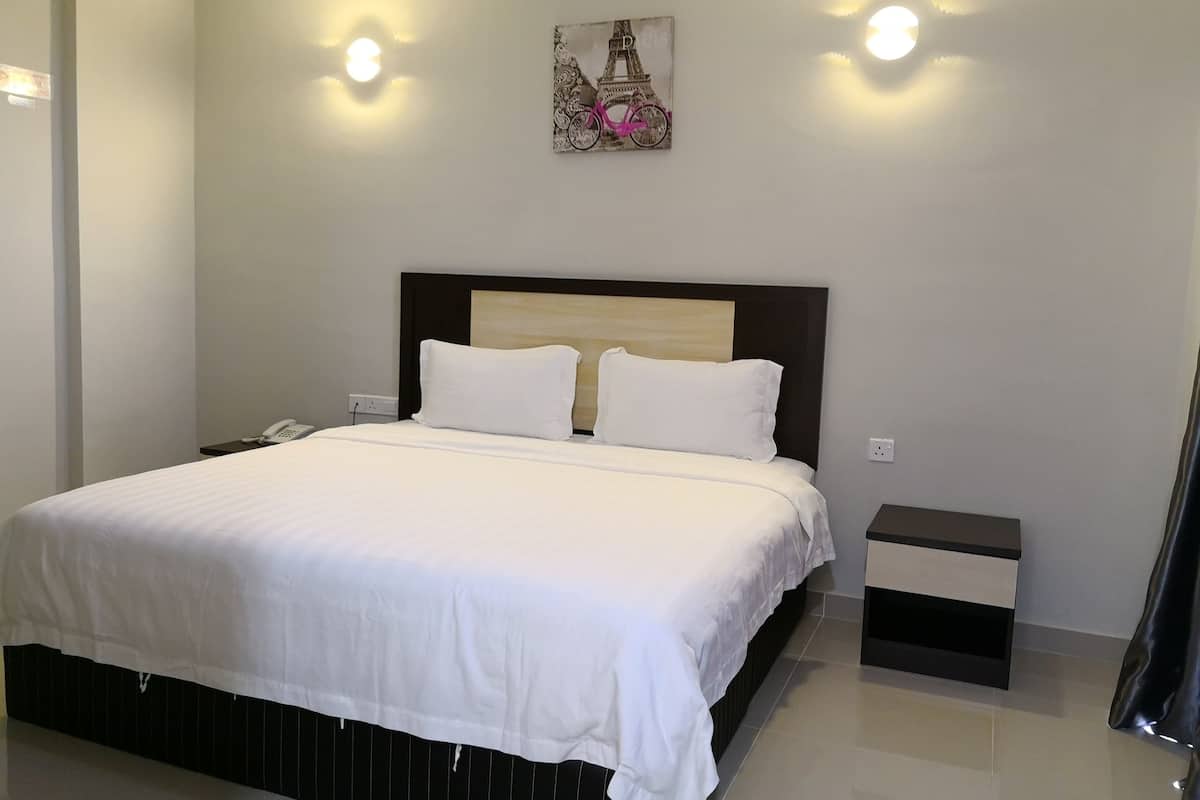 A modern hotel room with a large bed, bedside tables, and a painting of the Eiffel Tower.