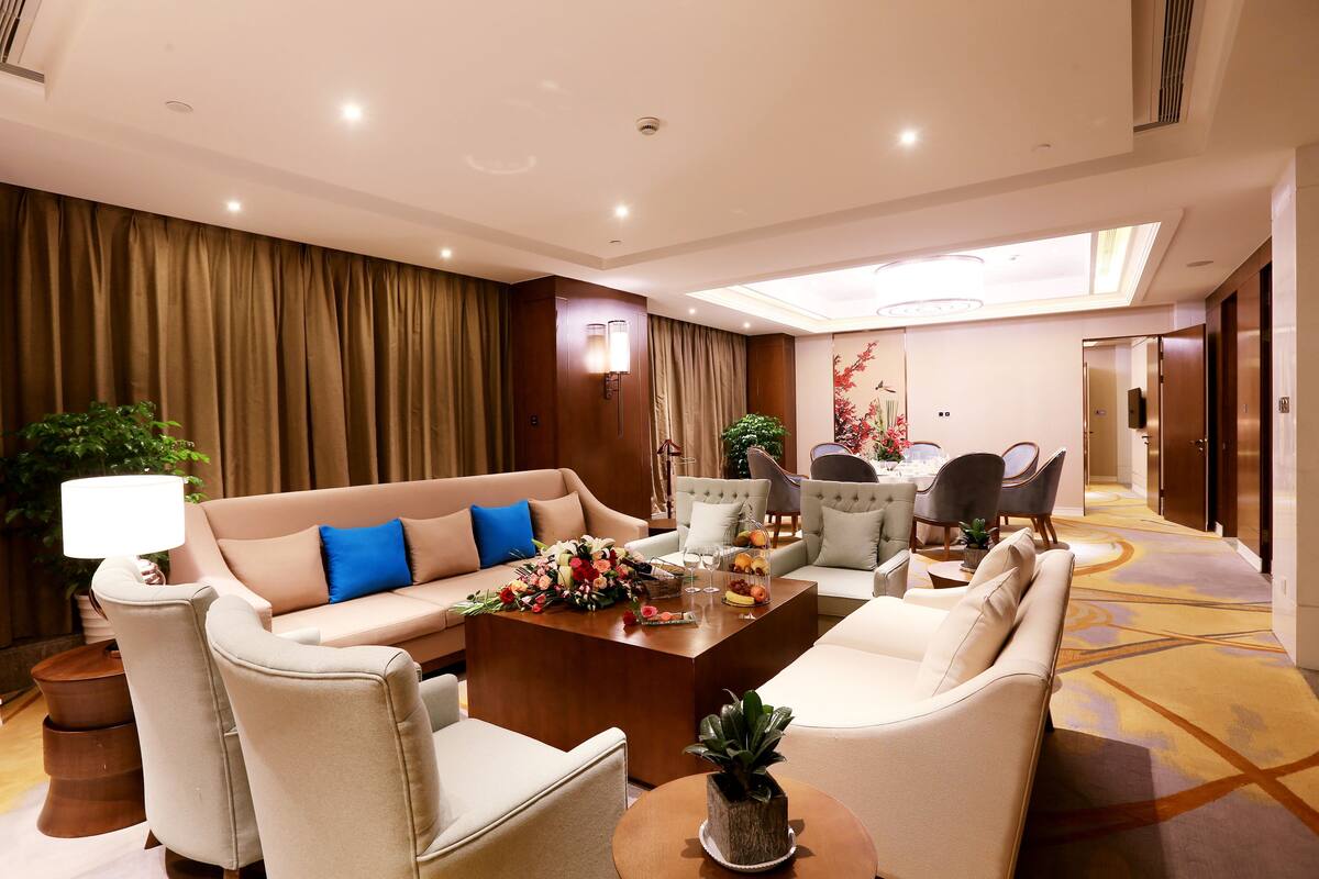 Un hall d’hôtel moderne avec un canapé, des fauteuils, une table basse agrémentée de fleurs et un espace repas.