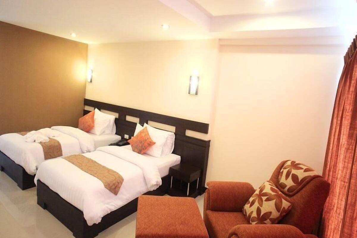 A hotel room with two beds, a sofa, and a small table.