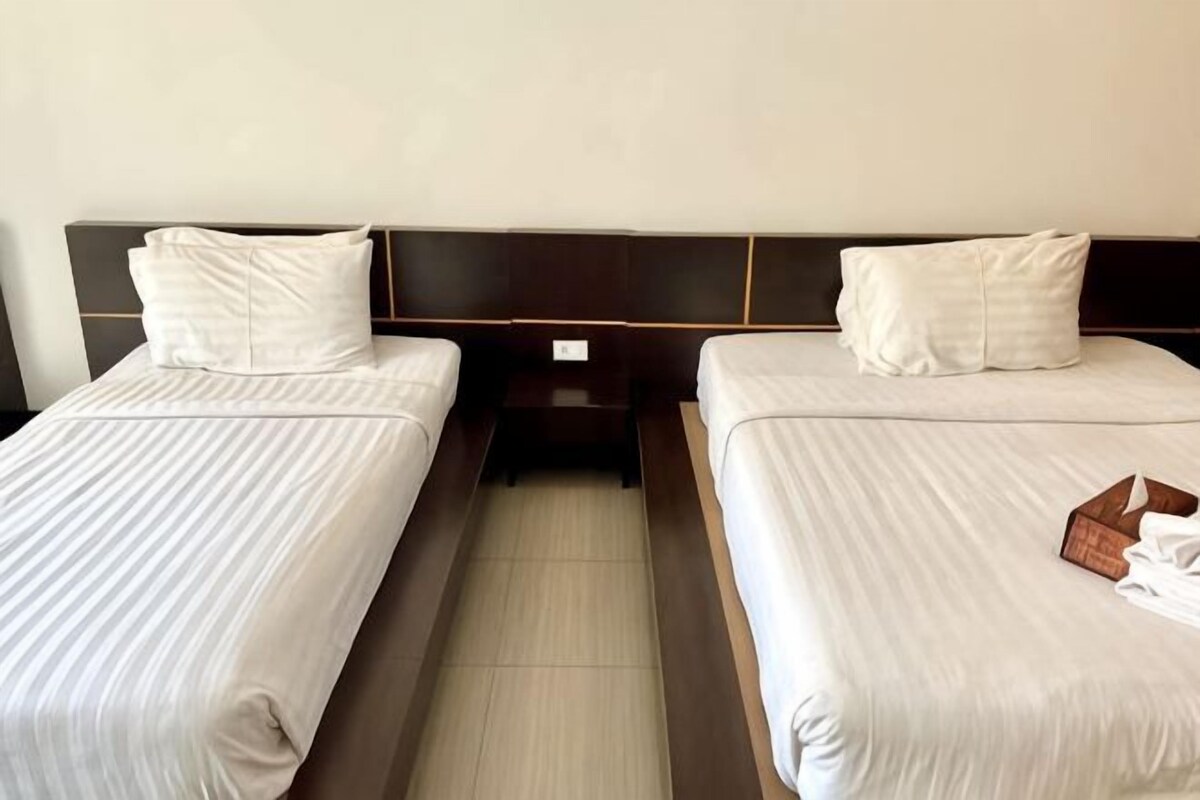 Two single beds with headboards, a nightstand, and a wooden box on the right bed.