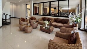 A spacious lobby with wicker furniture, large windows, and hanging pendant lights.