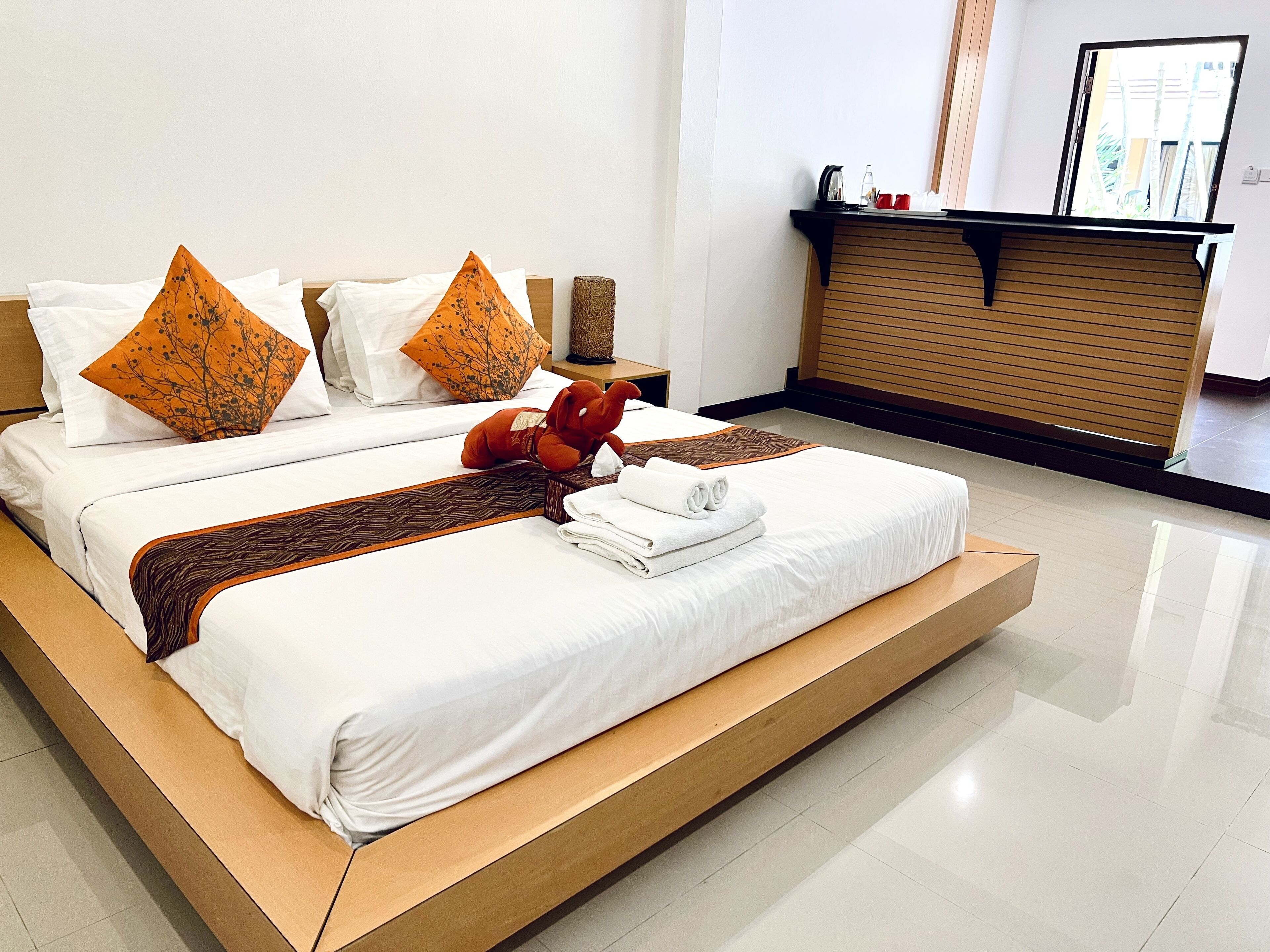 Une chambre d’hôtel moderne avec un grand lit, deux oreillers, un jouet en peluche et des serviettes soigneusement pliées.