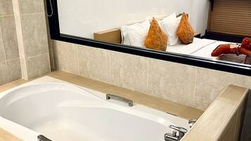 A modern bathroom with a large bathtub, a mirror, and a wooden vanity with a sink.